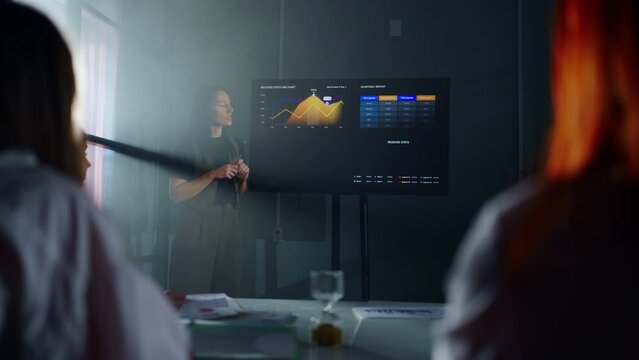 Woman Financial Analyst Showing Report Of Sales And Profits On Digital Display For Co-Workers