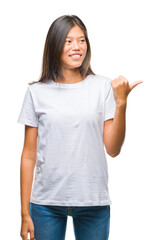 Young asian woman over isolated background smiling with happy face looking and pointing to the side...