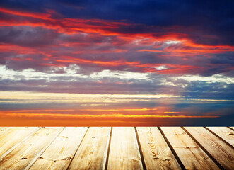 Wooden table on sky background and sunset light	
