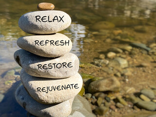 Relax, restore, refresh and rejuvenate text written on pebbles stack with nature background  Wellness lifestyle concept. 