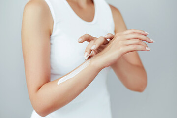 Closeup shot of woman hands holding cream and applying moisturizing hand cream. Beautiful female...