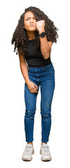 Young beautiful woman with curly hair angry and mad raising fist frustrated and furious while...