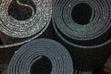Old sheet rubber of black color, twisted into rolls, top view. rubber waste.