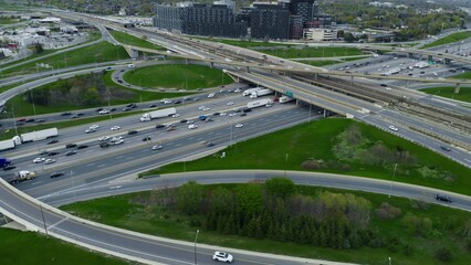 Aerial view over highway expanse, commuter cars threading through city's vascular roadways. Drone...