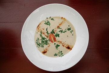 A large bowl of tahini from above placed on a wooden table