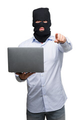 Business hacker man holding a computer laptop pointing with finger to the camera and to you, hand sign, positive and confident gesture from the front