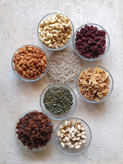directly above shot of healthy food nuts and dried fruits in glass bowls on stone table