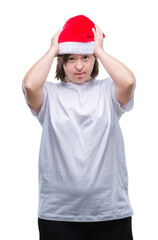 Young adult woman with down syndrome wearing christmas hat over isolated background suffering from headache desperate and stressed because pain and migraine. Hands on head.