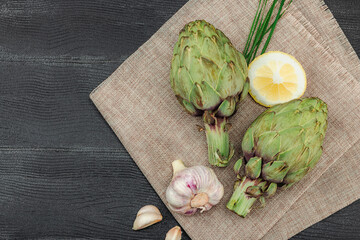 Fresh green artichokes cooking on wooden background. Traditional seasonal ingredients