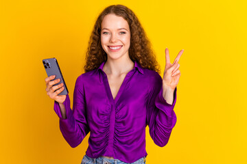Photo portrait of pretty young girl hold device show v-sign wear trendy violet outfit isolated on...