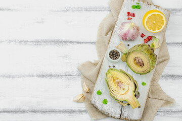 Fresh green artichokes cooking on wooden background. Traditional seasonal ingredients