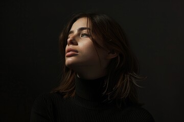 Fototapeta premium Young woman with a pensive expression in soft lighting, capturing a moment of introspection and subtle elegance.