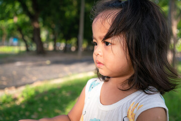 Fototapeta premium Toddler asian girl enjoying on green meadow grass sunset city park
