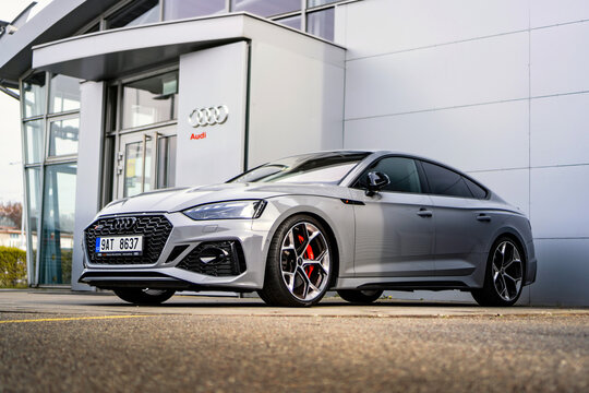 A gray Audi A7 luxury sports sedan stands outside a car dealership.
