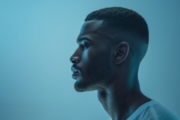 Side profile of a young man with a thoughtful expression, blue lighting enhancing his contemplative mood.

