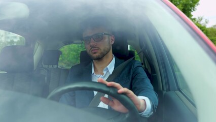 Businessman wearing glasses and suit while driving through the city. Transport, business, lifestyle and people concept. Real time