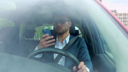 Stylish man talking on the mobile phone while driving his car in the city. Transport, business, technology and people concept. Real time