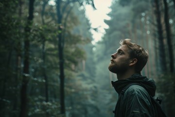 Young man in a contemplative pose, surrounded by a foggy forest, evokes a sense of mystery and exploration.

