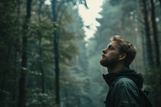Young man in a contemplative pose, surrounded by a foggy forest, evokes a sense of mystery and exploration.

