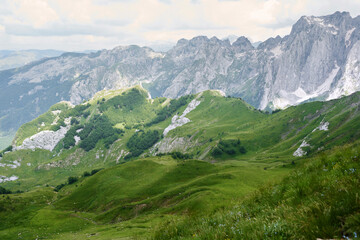 Mountain trail curving through alpine beauty. A hiker's path meanders along a green ridge,...