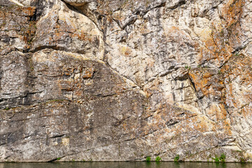 a stone cliff above the water, the texture of the rock and trees