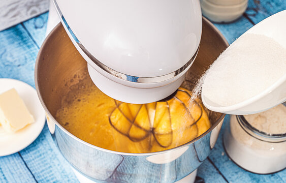 Sugar is poured into the bowl of a planetary mixer with beaten eggs. Recipe Crepe suzette. Selected focus