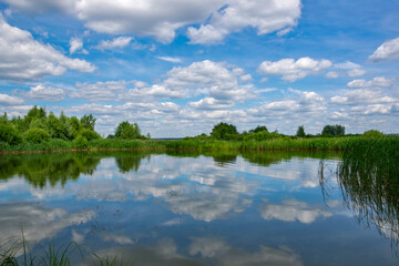 Quiet river backwater with beautiful reflection of clouds in the water