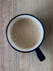 Coffee in a cup on wooden table. Top view.