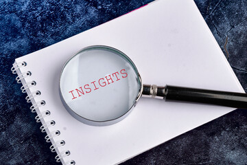 Insight concept. INSIGHTS word through a magnifying glass in a notebook on a beautiful blue...