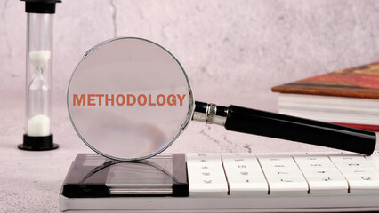 METHODOLOGY CONTEPT. METHODOLOGY word through a magnifying glass on a calculator with an hourglass...