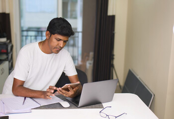 Young indian man working on laptop computer at home office Work from home concept