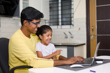 indian father and daughter using laptop at home in the living room father wearing eyeglass