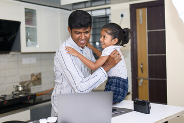 indian father helping his little daughter with homework and using laptop at home