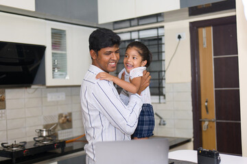 Happy father and daughter using laptop in the kitchen at home. Fathers day concept