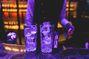 Bartender working, beautiful row line of different coloured liquor alcohol cocktails on a party in...