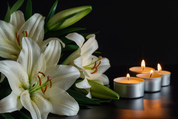 Elegant white lilies and glowing candles on a dark backdrop, symbolizing peaceful condolences and remembrance at a funeral setting