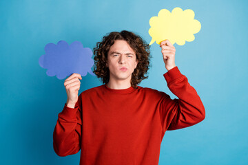 Photo of funky doubtful guy dressed red pullover rising mind clouds emtpy space isolated blue color...