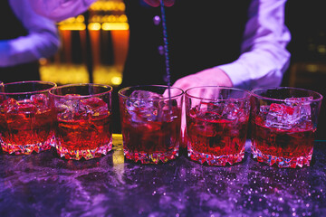 Bartender working, beautiful row line of different coloured liquor alcohol cocktails on a party in...