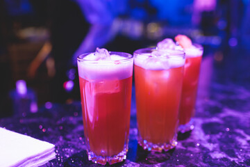 Bartender working, beautiful row line of different coloured liquor alcohol cocktails on a party in...