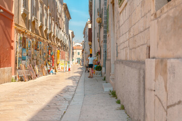 Rovinj, Croatia. Picturesque Mediterranean street with outdoor cafes people walking summer sun.