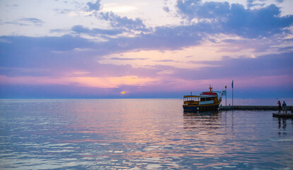Obraz premium Beautiful sunset over calm sea, with vivid colors and clouds in the sky. Serenity and nature concept