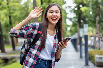 woman is smiling and waving at the camera while holding a cell phone