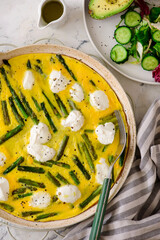 Omelet with asparagus and goat cheese in a pan with avocado and green salad