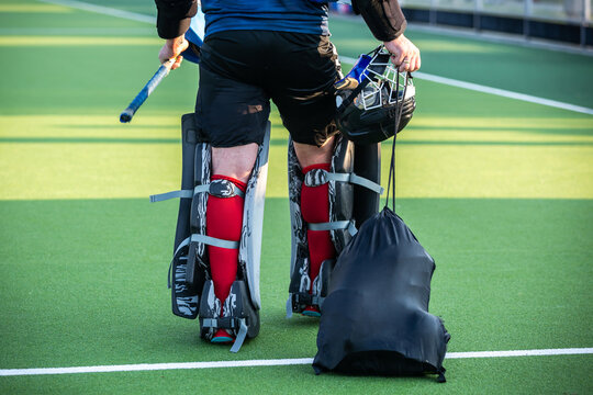 Field hockey theme: A field hockey goalkeeper carrying and wearing Field Hockey Goalie gear Full Set.