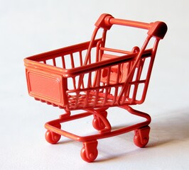 A small toy shopping cart on a white surface. - obrazy, fototapety, plakaty