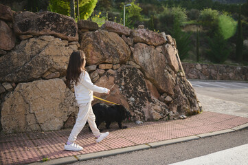 Full length portrait of a cute little child girl in sportswear, taking her purebred cocker spaniel...