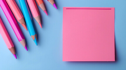 Back to school concept. A pink color post it paper, pink and blue pencils on pastel blue background with copyspace.