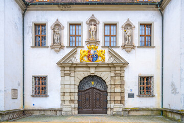Fototapeta premium Ornate entrance door of the Old Chateau in Bad Muskau, adorned with statues and a colorful coat of arms. Saxony, Germany