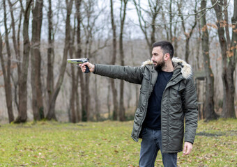 Young man aims and shoots with a gun in the forest