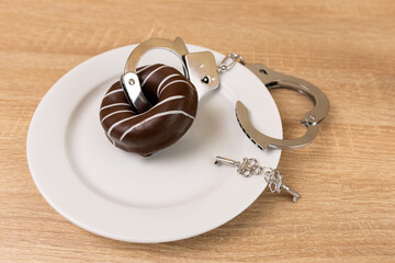Chocolate donut with handcuffs and keys. Passion for sweets.